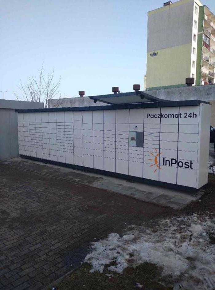 Поштомат GDY16N Z boku pasażu handlowego, za garażem blaszanym