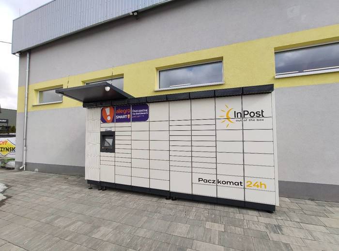 Paczkomat JQN01M Przy ścianie po lewej stronie budynku