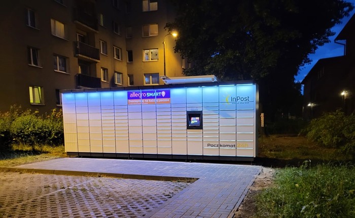 Paczkomat KAT142M przy parkingu, przed budynkiem mieszkalnym
