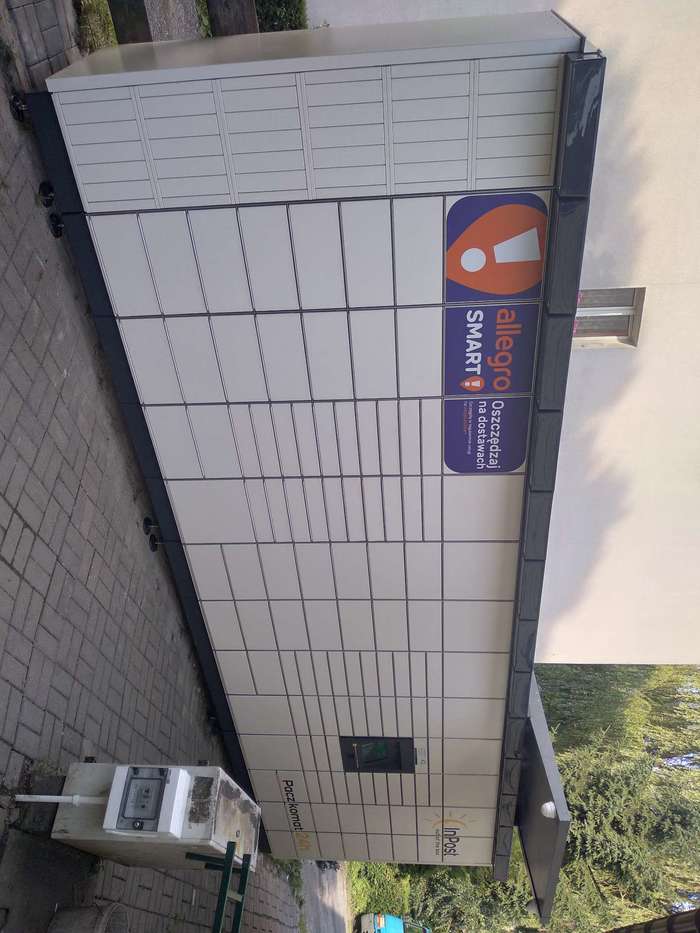 Paczkomat KGR04M Po lewej stronie od wejścia o sklepu.