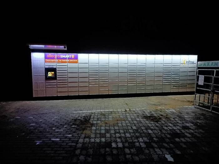 Paczkomat KOB06M Na stacji Axan, na parkingu po prawej stronie budynku