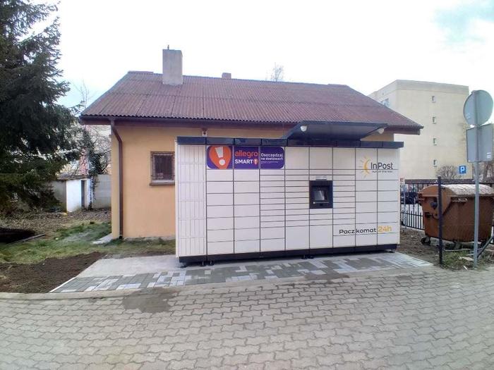 Paczkomat KOO05M obok sklepu, centralka i skrytki odwrócone w stronę chodnika