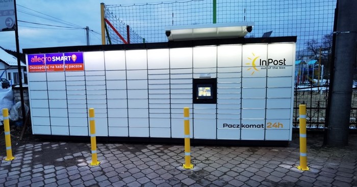 Paczkomat KOU01M Na parkingu sklepowym przy płocie