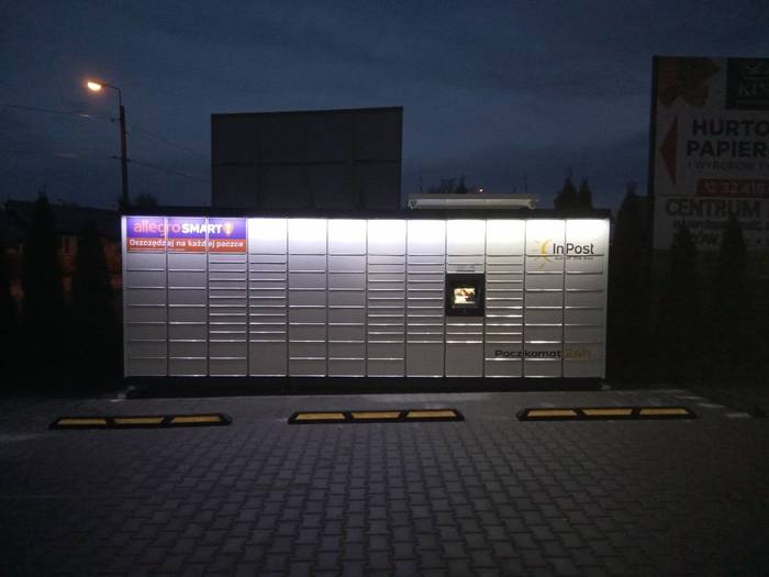 Paczkomat LUM04M na parkingu, po prawej stronie wejścia do sklepu Żabka