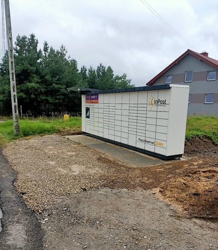Paczkomat OLK11M na parkingu przed budynkiem,