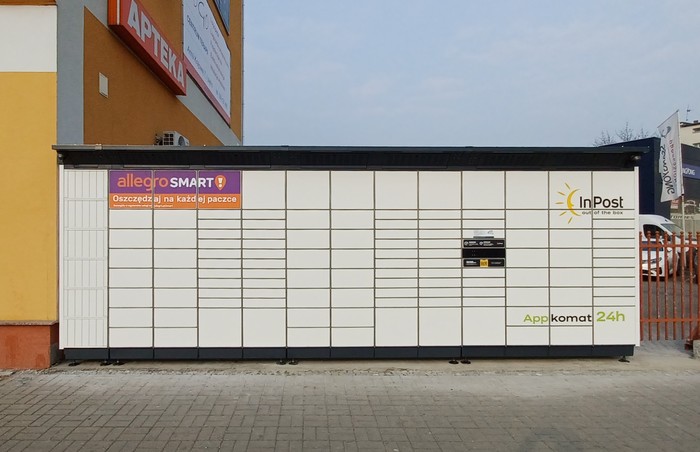 Paczkomat OPO11BAPP na parkingu po prawej stronie budynku usługowego