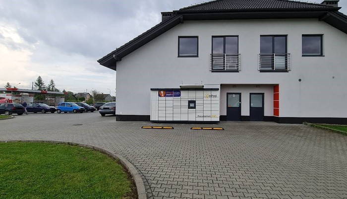 Paczkomat PZW01M przy sklepie Delikatesy Centrum i Apteka w budynku obok stacji ORLEN i myjni samochodowej