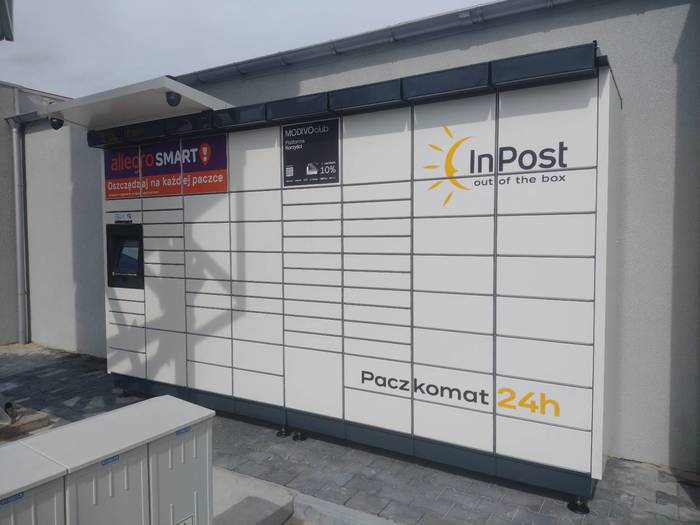 Paczkomat RAC20M na parkingu parku handlowego M Park, obok pylonu reklamowego