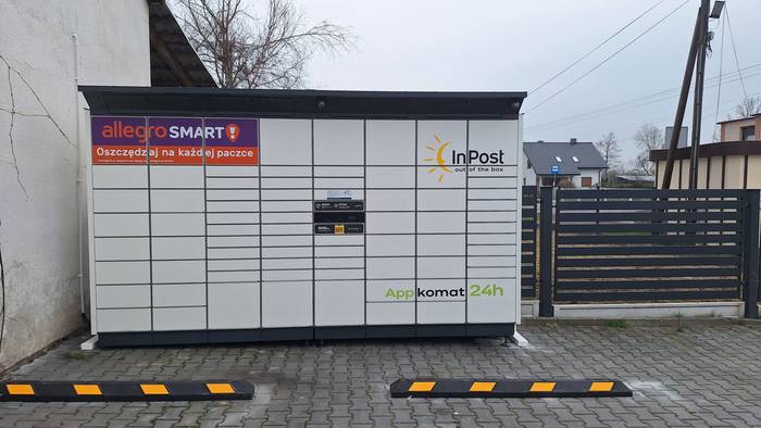 Paczkomat RUDO01BAPP na parkingu obok sklepu