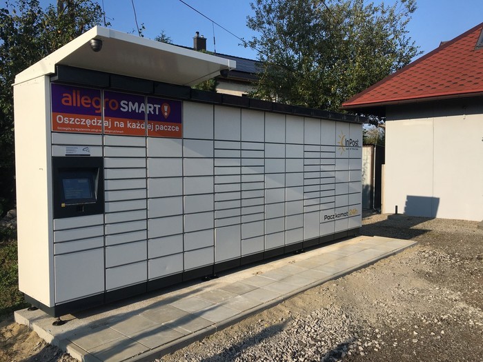 Paczkomat RZI02M na parkingu przy budynku usługowym