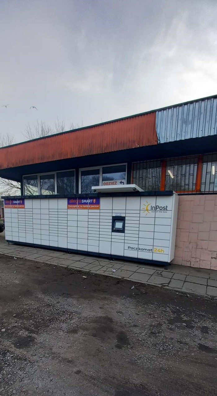 Paczkomat SZC106M Na ścianie przy drodze dojazdowej do parkingu