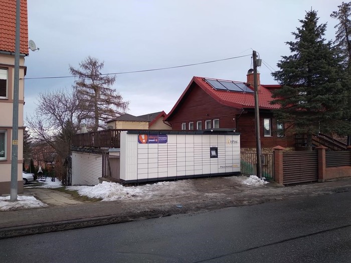 Paczkomat WAL20M Od przodu budynu, przy drodze.