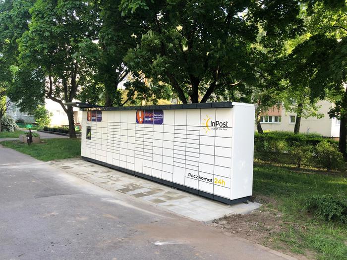Paczkomat WAW385M W środku osiedla, przy wiatach na śmieci