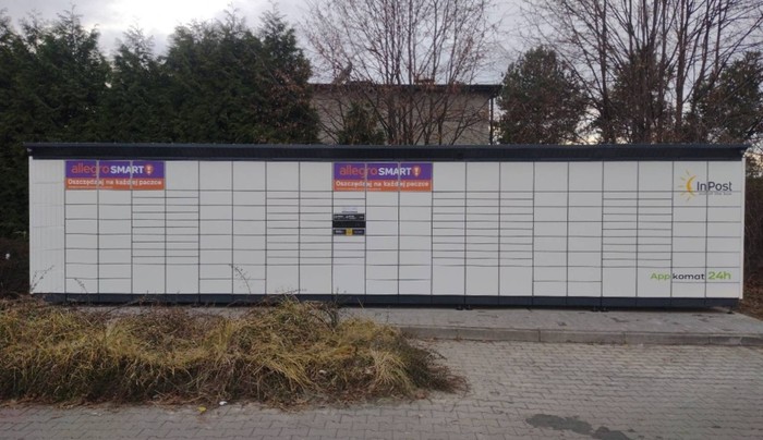 Paczkomat WOA01BAPP na parkingu obok sklepu