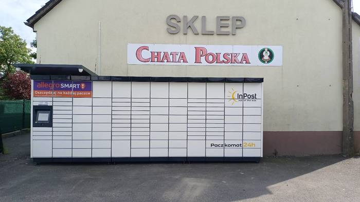 Paczkomat XZZ01M Po lewej stronie od wejścia do sklepu.