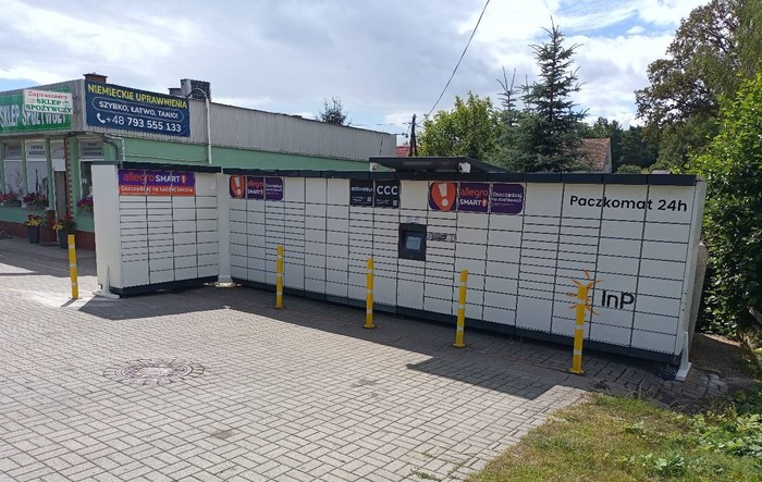 Paczkomat ZRE01M Po prawej stronie od wejścia do sklepu.
